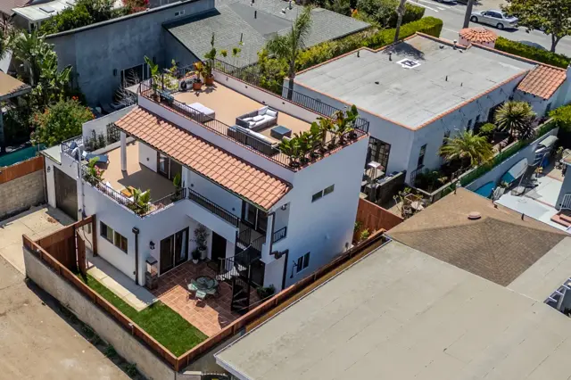 West LA two-story ADU with Mediterranean tile roof and 600 sqft wraparound rooftop deck — aerial view showing outdoor dining and lounge setup