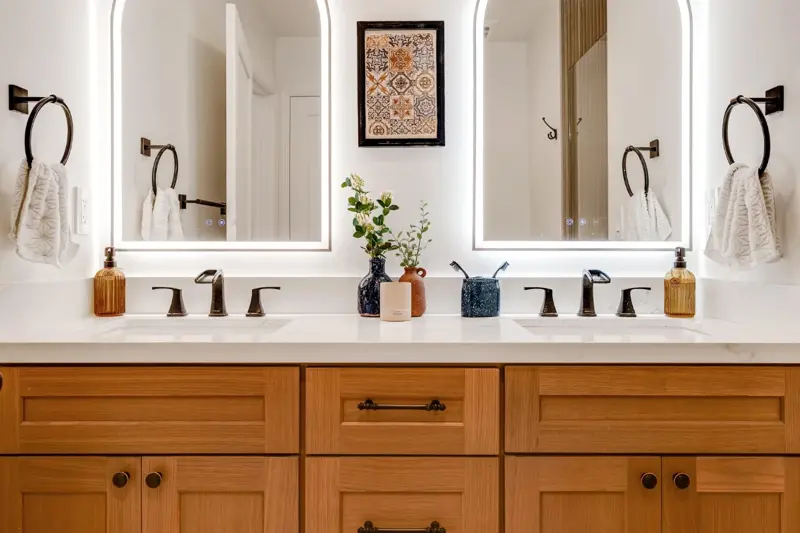 West LA ADU primary bathroom with dual vanity, oak cabinetry, framed mirrors, and matte black plumbing hardware