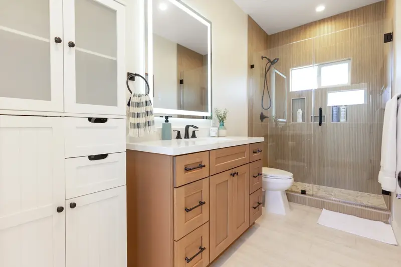 West LA ADU secondary bathroom with frameless walk-in shower, single oak vanity, and full-height storage