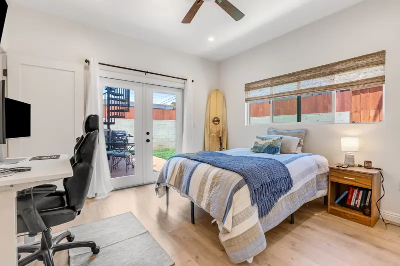West LA ADU bedroom with French doors to private patio, ceiling fan, light wood floors, and California coastal styling