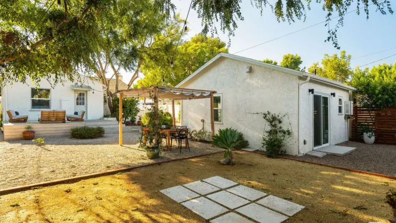 Private pergola-covered patio of Burbank garage conversion ADU with outdoor dining table, paver hardscape, and shared backyard beyond