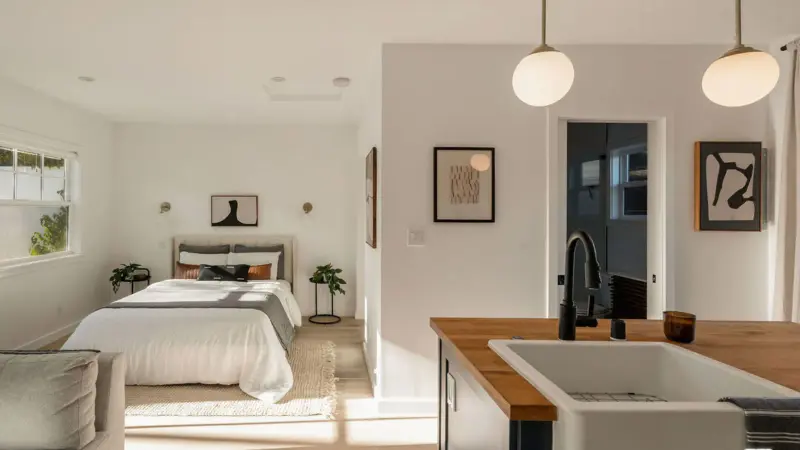 Sleeping area of Burbank studio ADU with globe pendants over the kitchen island sink in the foreground