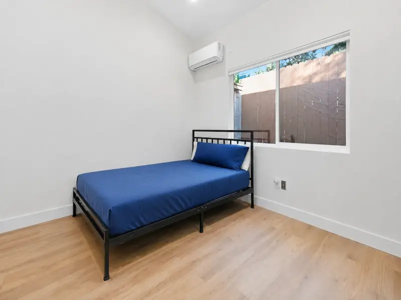 Mar Vista ADU bedroom with a large slider window to the side yard and wide-plank wood-look flooring