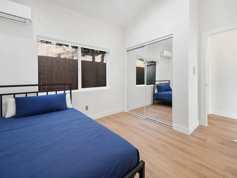 Separate bedroom in the Mar Vista garage conversion ADU with mirrored sliding wardrobe doors, mini-split head, and vaulted ceiling