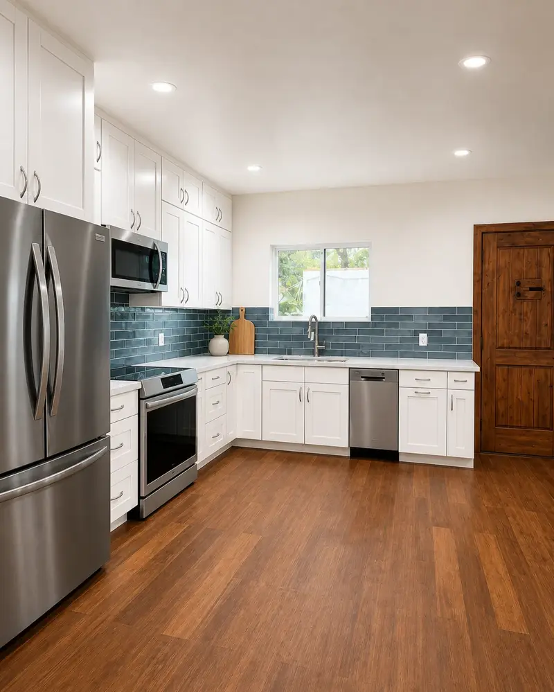 Van Nuys ADU kitchen range wall — slide-in stainless range, over-range microwave, French-door refrigerator, and warm wood-plank flooring