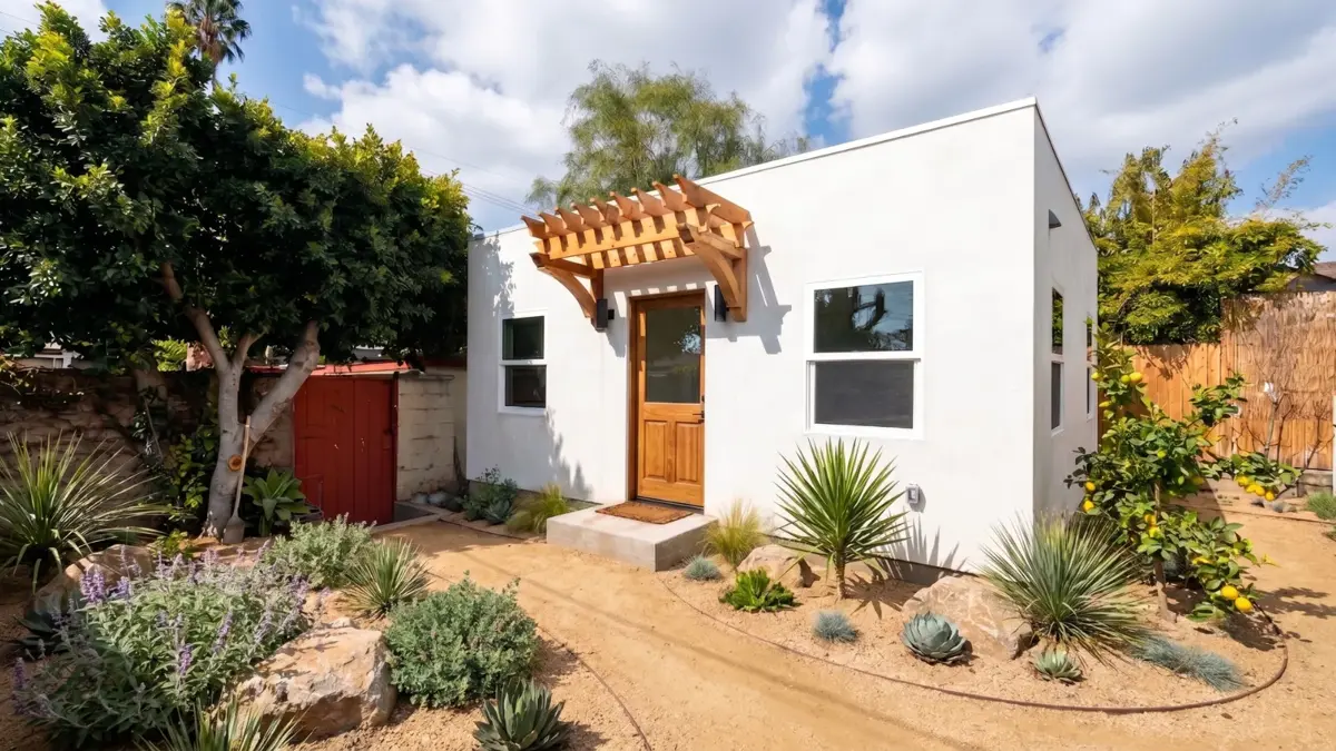 The Wilshire ADU built complete in a West LA HPOZ — white stucco exterior with a wood pergola over the entry and drought-tolerant landscaping