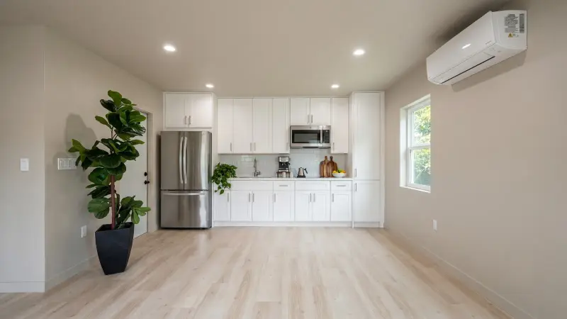 Interior of the West LA HPOZ Wilshire ADU — full kitchen with white shaker cabinetry, stainless appliances, and light wood floors in an open studio volume