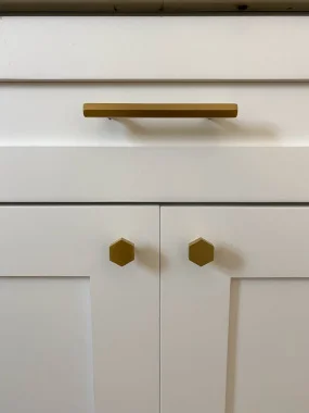 Brushed gold hardware of white shaker kitchen cabinets.