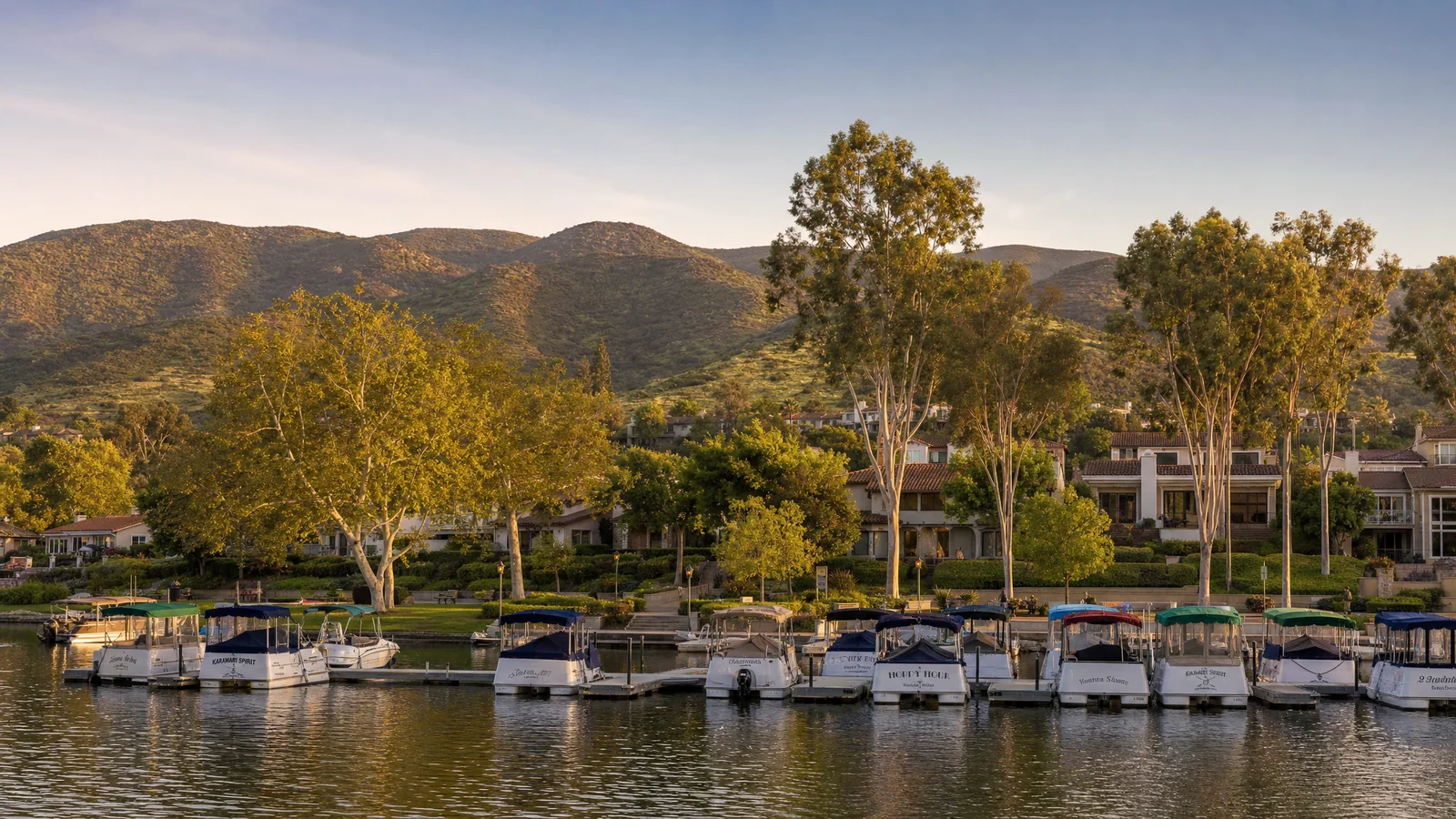 Building an ADU in Westlake Village, CA — boats moored along the Westlake Lake shoreline below tile-roofed lakeside homes and the Conejo Valley ridgeline, in the master-planned city where CALI ADU designs and permits backyard ADUs under WLVMC § 9.14.070.