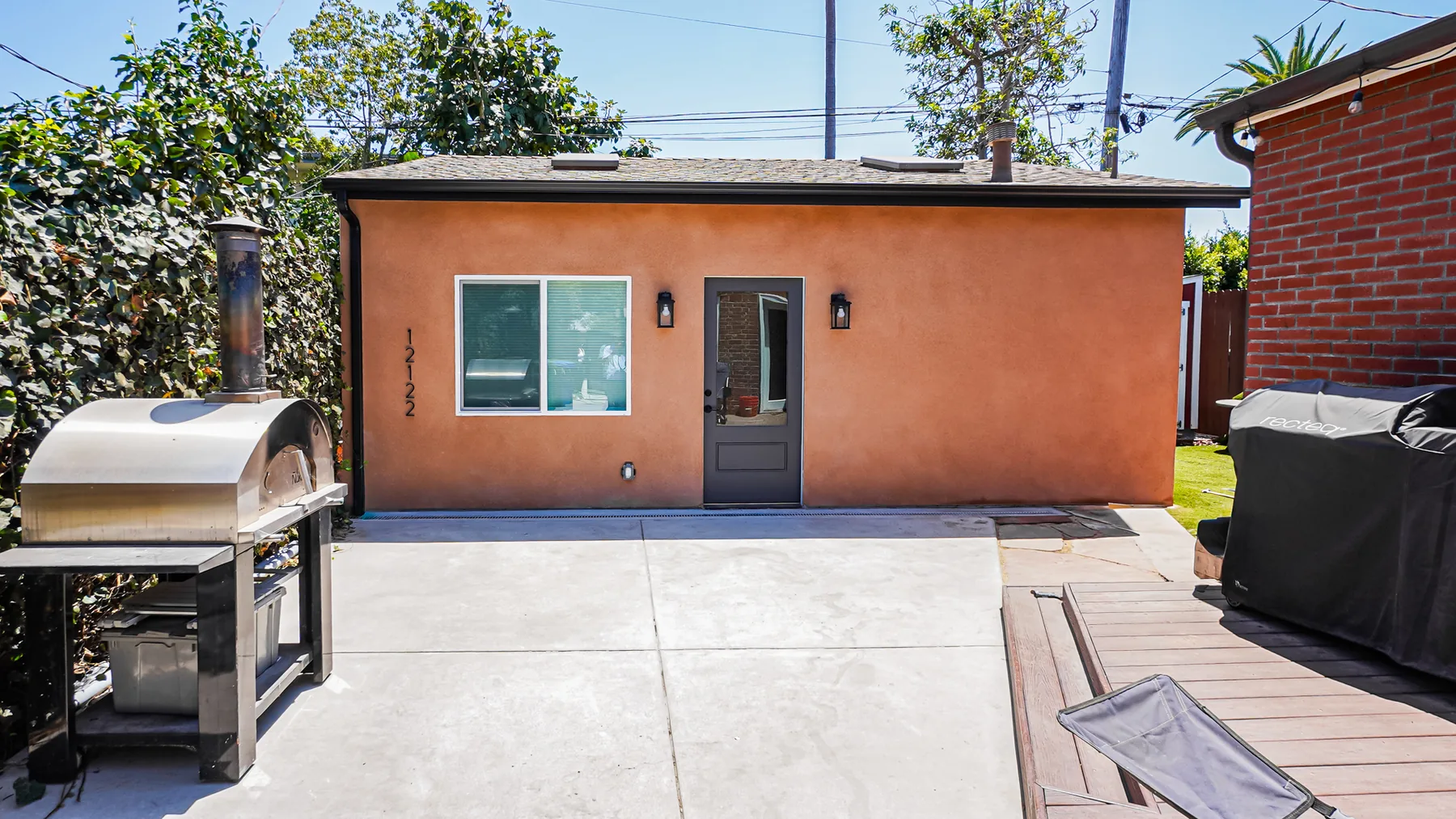 Mar Vista garage conversion ADU — custom terracotta stucco exterior with black lantern sconces, bronze gutters, and a private concrete patio